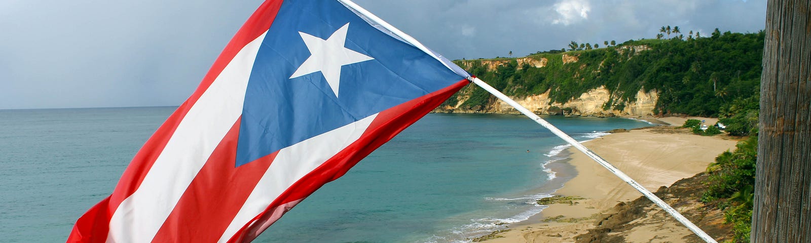 The Puerto Rican flag is flying over a beach.