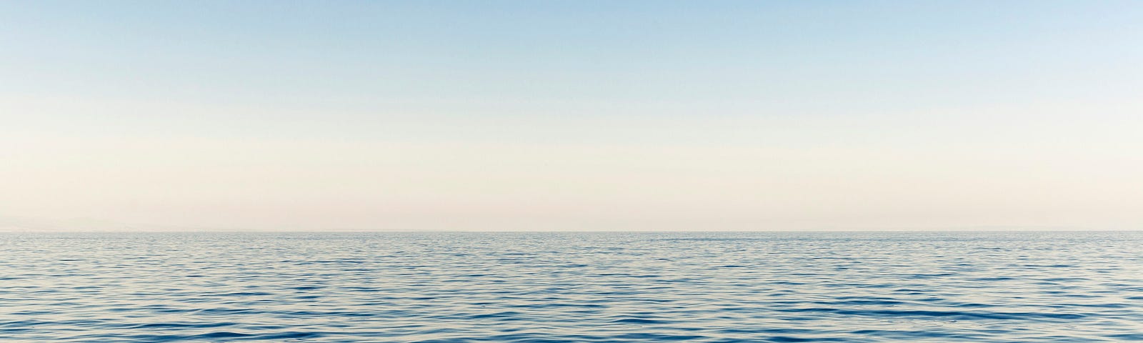 Blue sky over dark blue water; Tide but no real waves