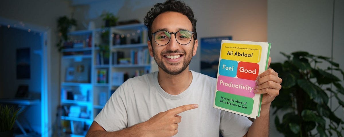 Ali Abdaal holding a copy of Feel-Good Productivity