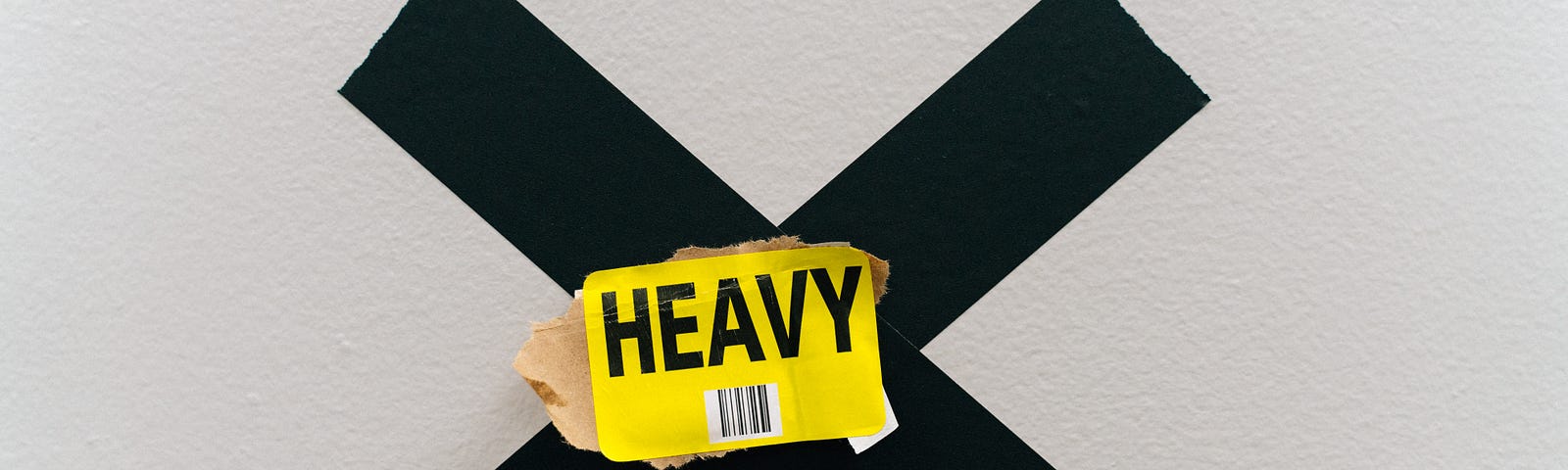 this is a picture of a solid black X with a yellow piece of paper on top that says, “heavy”