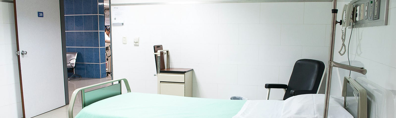 White room with a hospital gurney, a chair and some medical supplies.