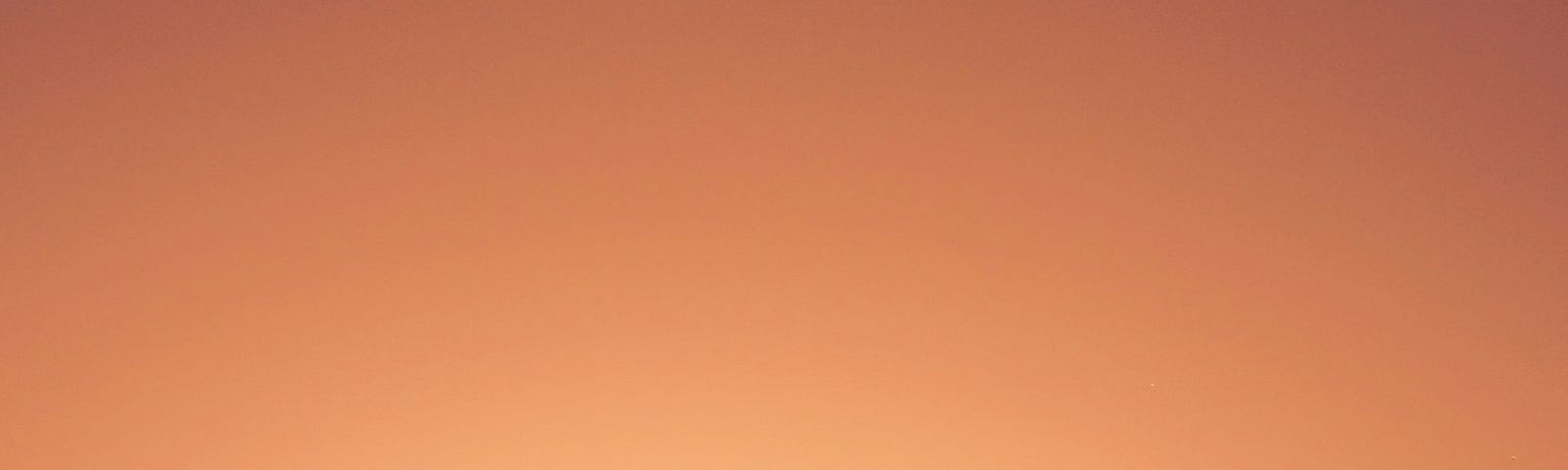 woman with fist in the air in resistance on an orange background of sunset