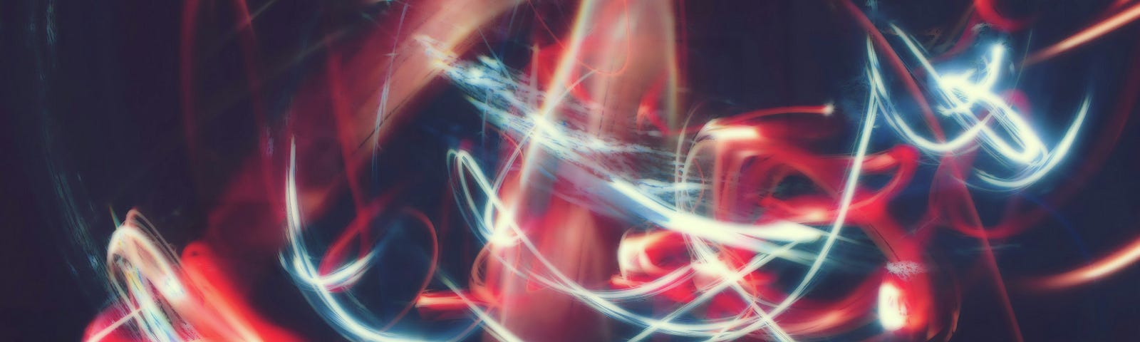 An abstract image of swirling, moving lines of light, blue intersecting with red, against a dark purple/black background.