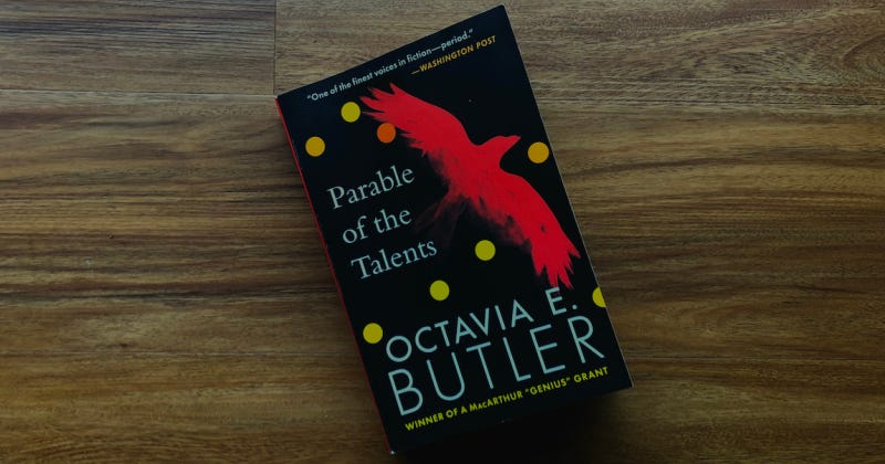 A paperback copy of Parable of the Talents by Octavia E. Butler against hardwood.