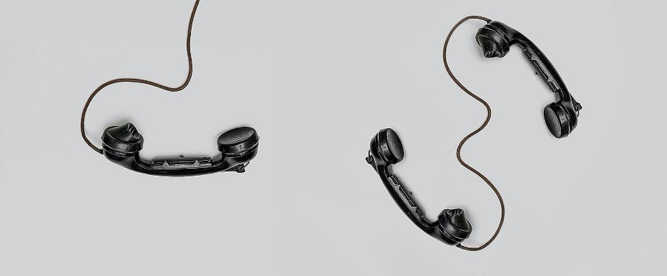 black telephones with swirled wires on a grey background