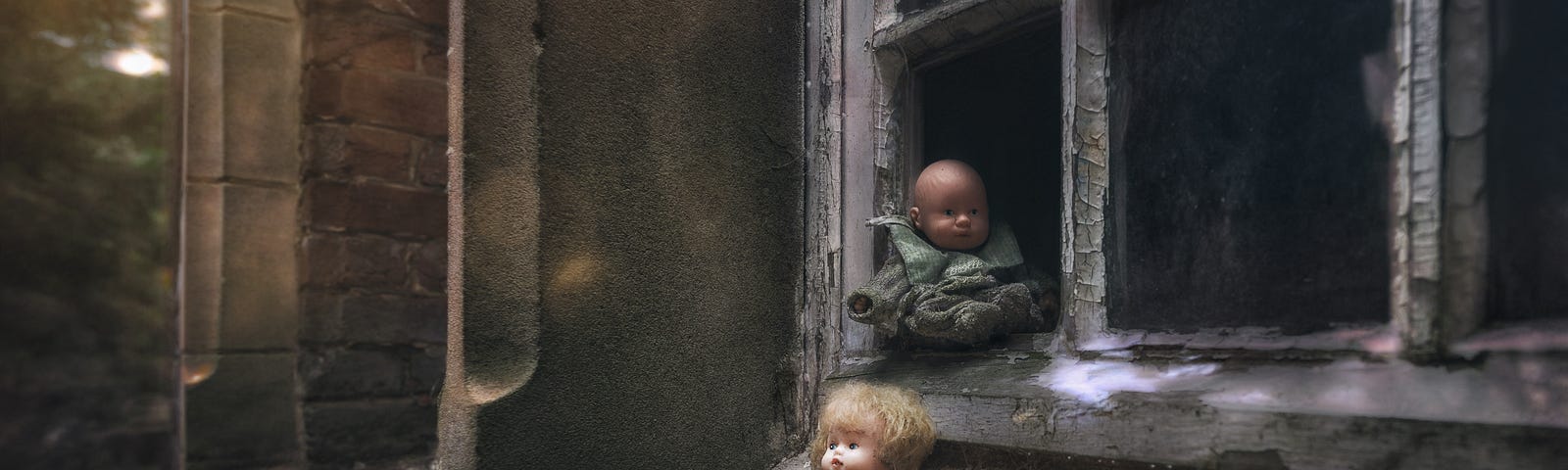 Dolls sitting outside leaning against window of a creepy house.