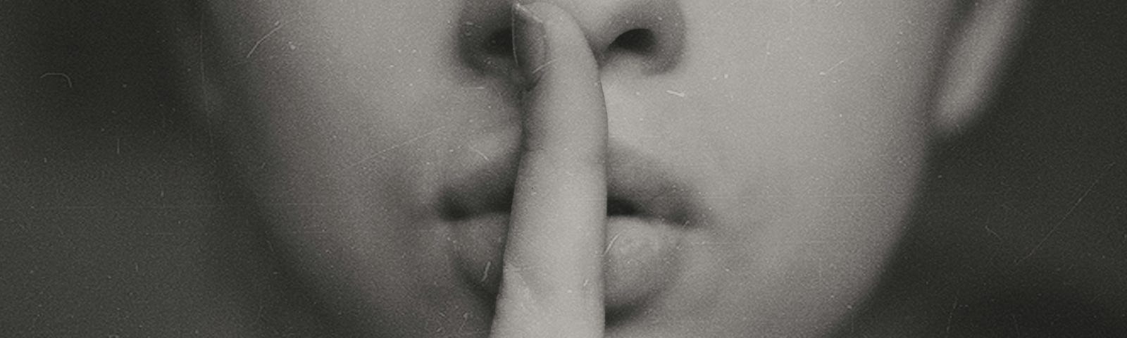 A picture of a woman with her finger over her lips denoting quiet.