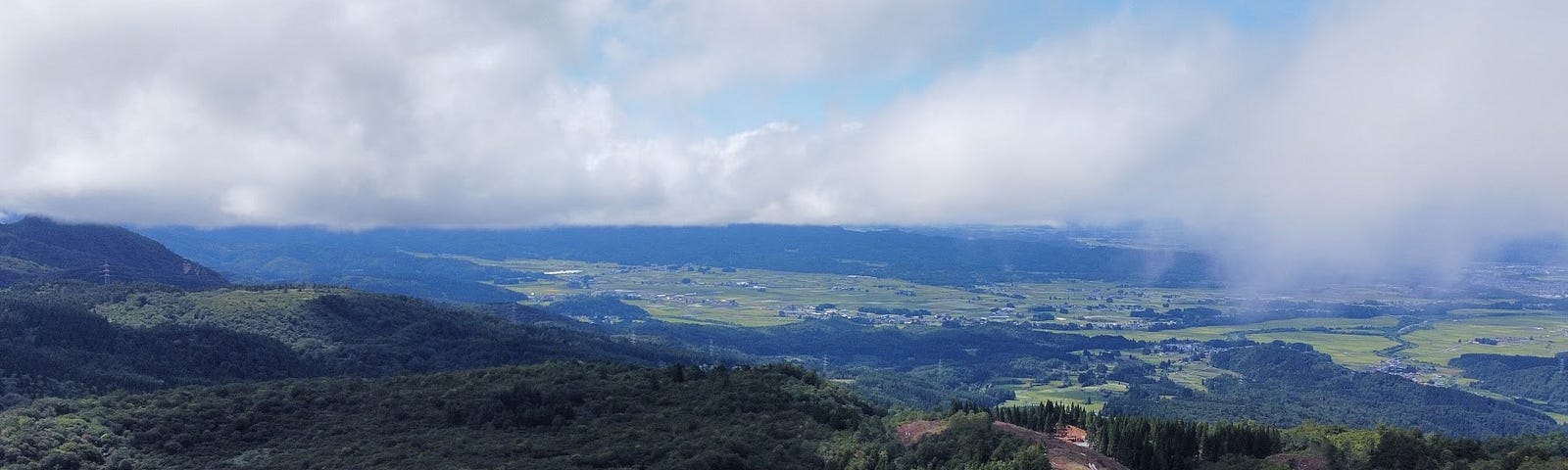 The green landscape of Obanazawa City, home to Okina-san, with the Kurumi Daira pond in the foreground.