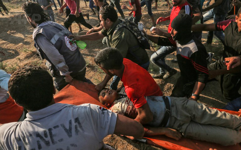 Enfermeros y manifestantes llevan el cuerpo de Othman Hilles, de 14 años de edad, después de que las fuerzas israelíes le dispararan y mataran cerca de la valla de separación de Israel, al este de la ciudad de Gaza, el 13 de julio de 2018. (Foto: AFP / Mahmud Hams)