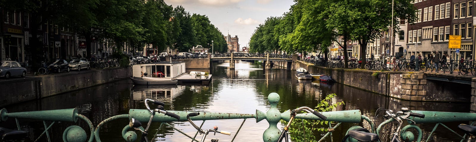 A view of an Amsterdam canal with several vintage bicycles in the foreground.