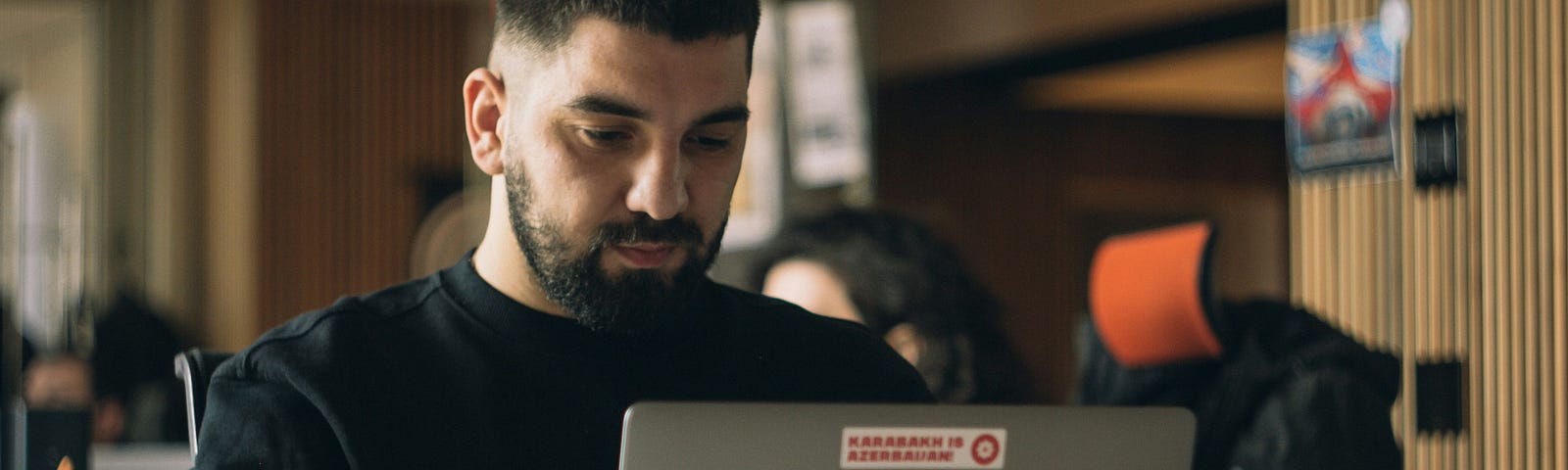 Bearded man wearing a black sweater typing on a portable computer in an office