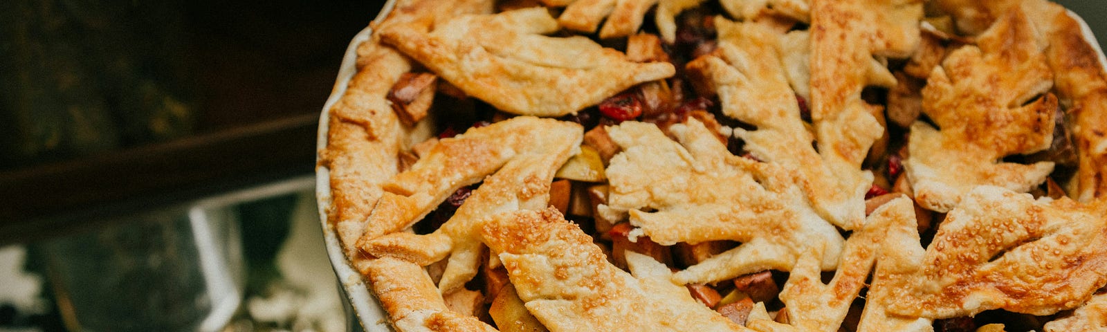 Beautiful apple pie in a china dish, with a top crust decorated with leaves made from pie dough.