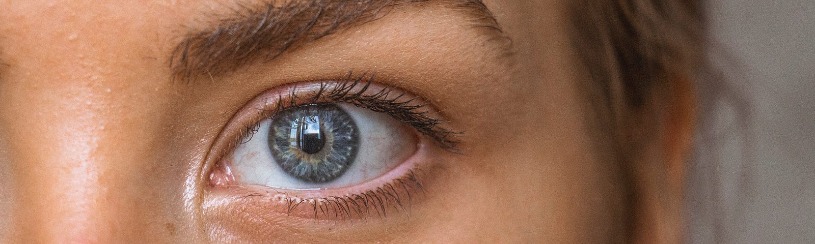 A young woman stares at us. We see her left face, including her blue-green eye. New research illustrates the potential of 3D retinal images — captured using optical coherence tomography (OCT) technology — to identify and accurately predict kidney disease progression.