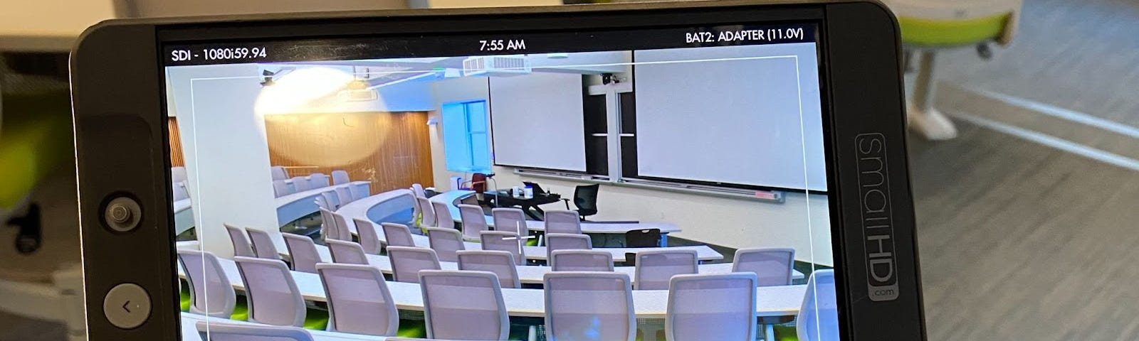 Empty chairs in a classroom, seen through a video monitor