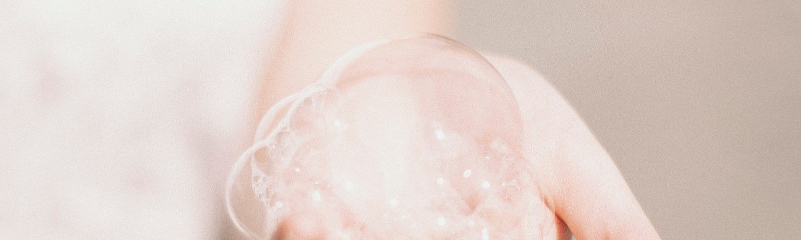 A child’s hand holds a mass of soap bubbles