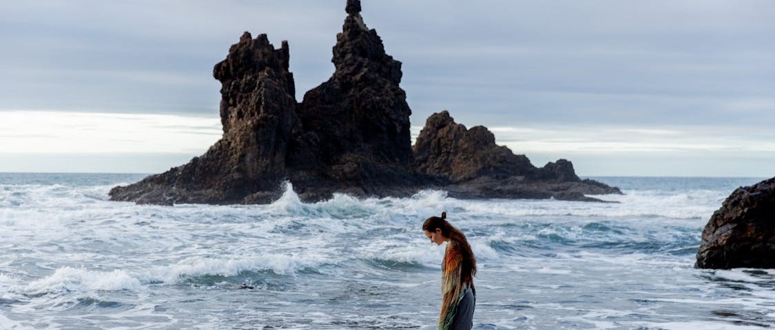 Lonely woman standsing on rocky coast.
