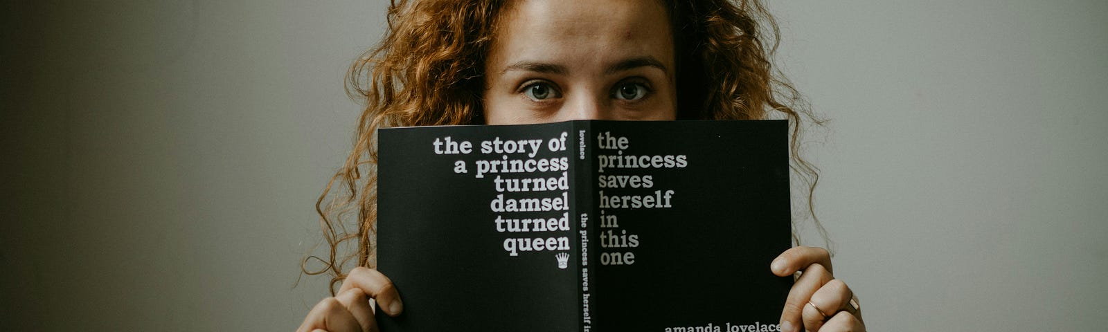 woman holding up a book that reminds us that the princess was always saved by the prince but this time in this book she save herself.