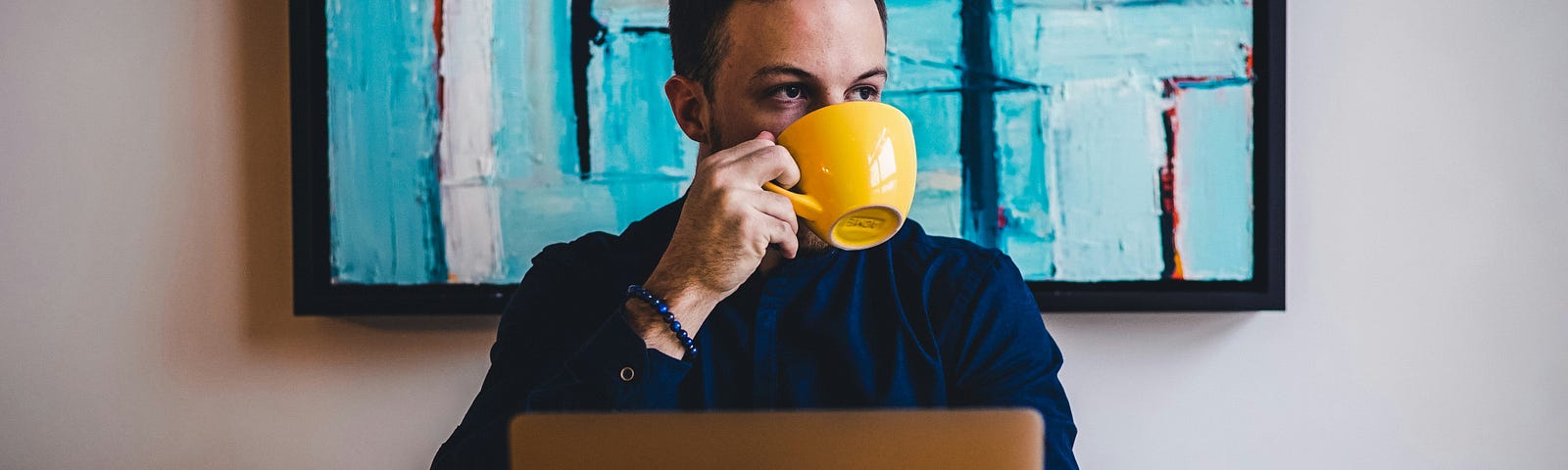 A man in his office drinking coffee from a yellow mug