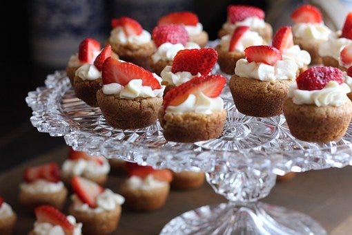 Muffins topped with strawberries and cream.