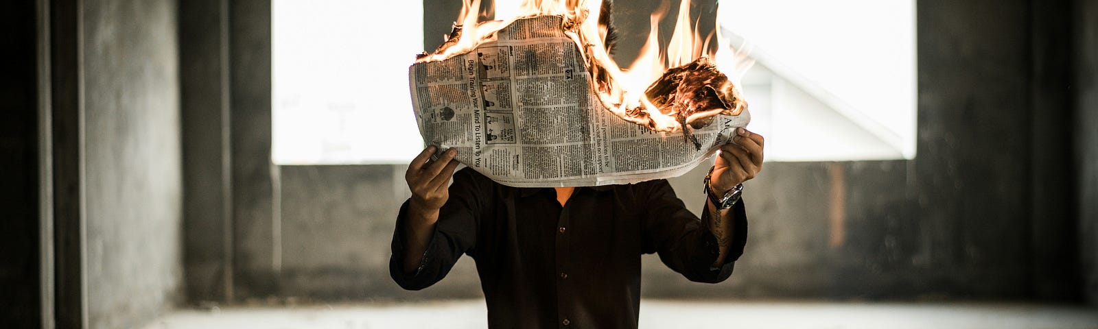 man reading newspaper that’s on fire