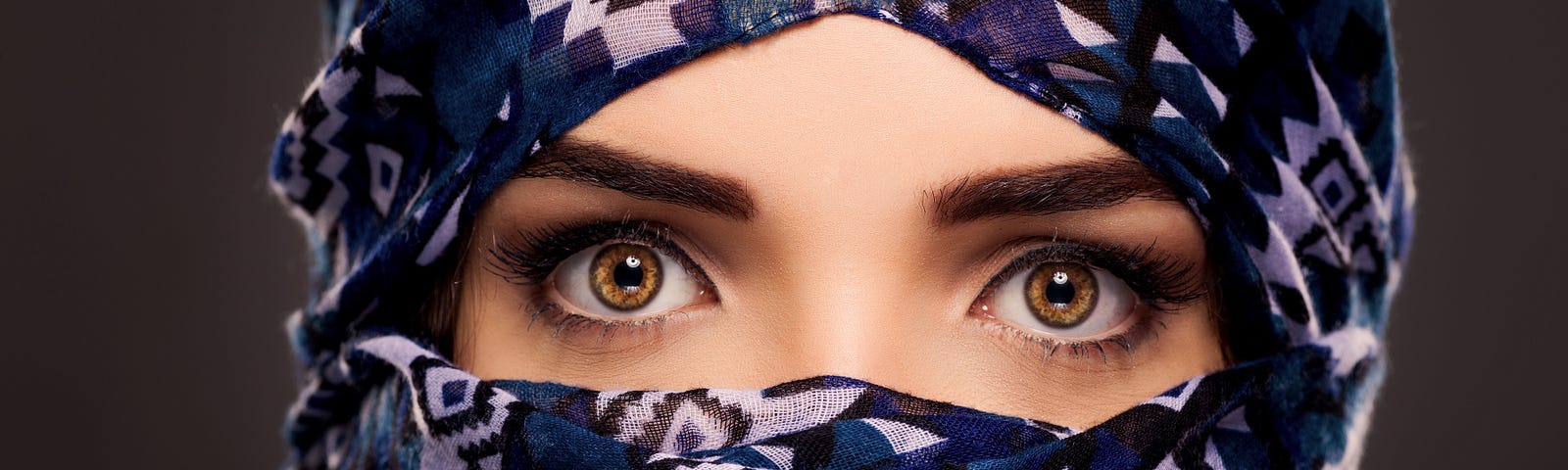 A woman with a head covering that only leaves her brown eyes exposed.