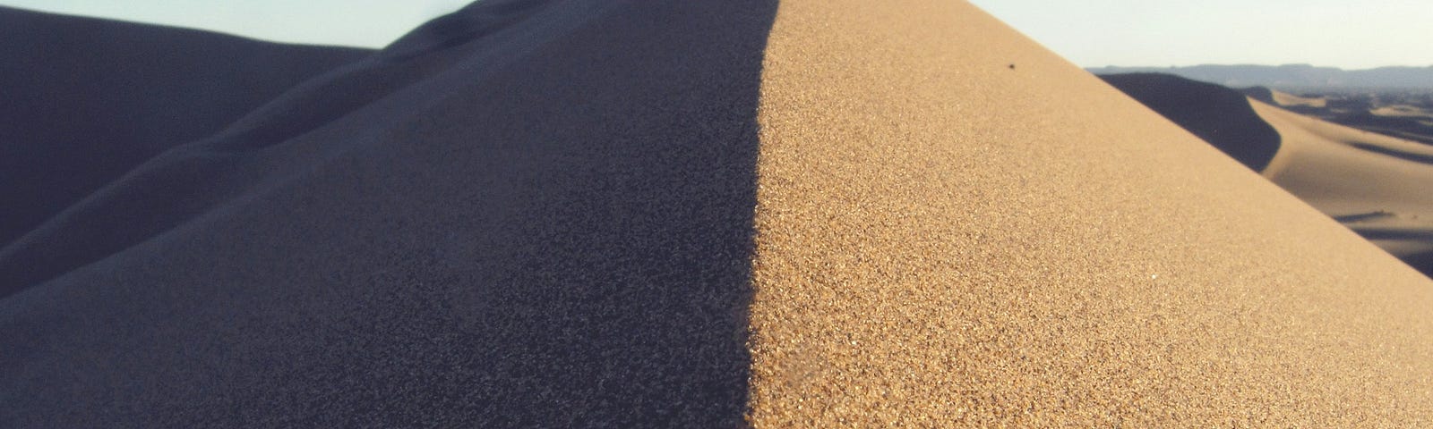 A sand dune, half light, half shadow. A way to represent how a person can be influenced by the people they’re around.