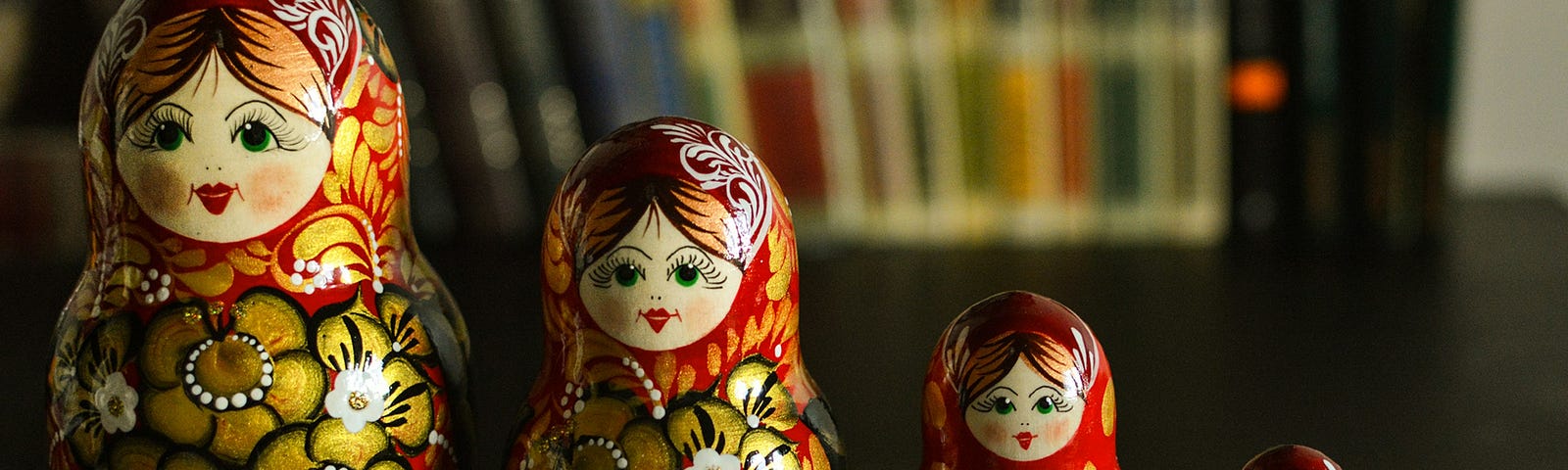 Russian dolls in five sizes of the same brand, painted red and gold. The faces are painted with a red mouth and a beautiful smile.