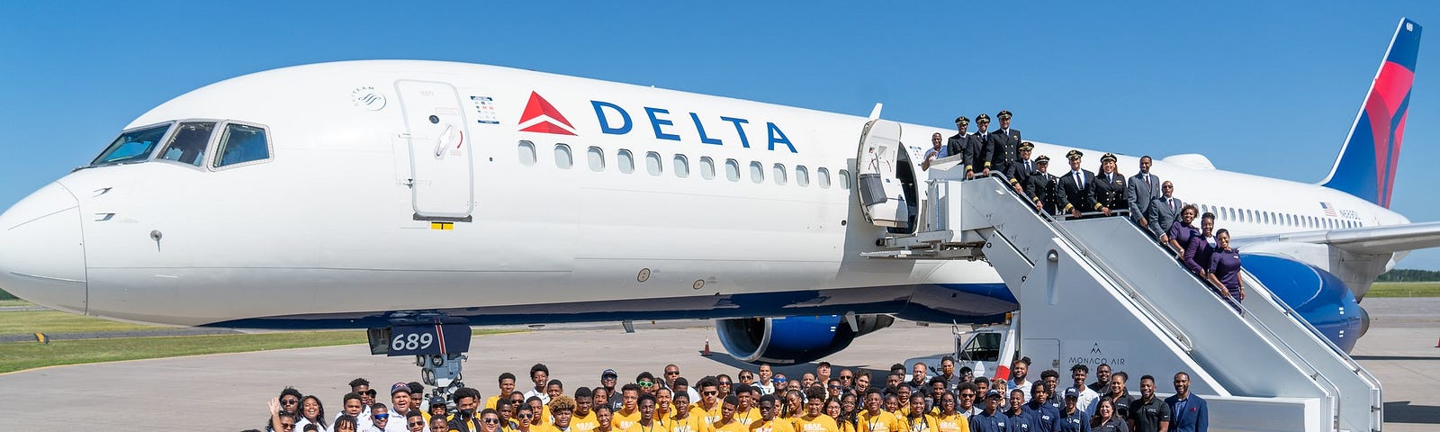A group shot of OBAP and ACE camp students posing with the air crew in front of the Boeing 757