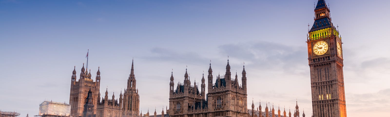 The UK Houses of Parliament at dusk, with Elizabeth Tower (Big Ben) on the right hand side, and light streams from traffic passing over Westminster Bridge in the foreground