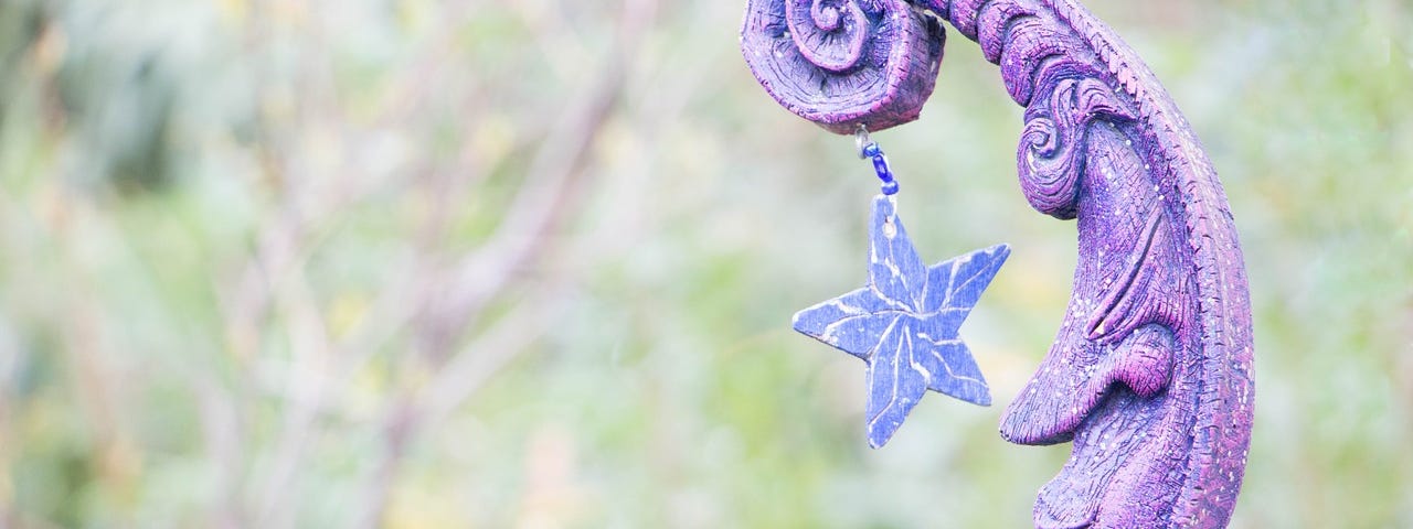 Purple man in the moon decoration with a star hanging down and a background of plants