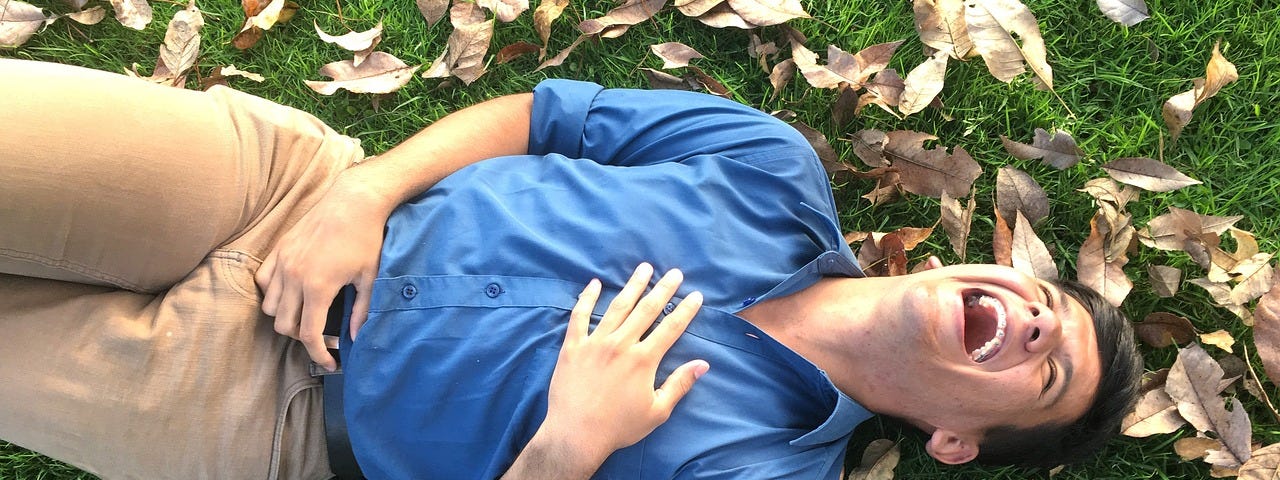 A laughing person lying on the grass.