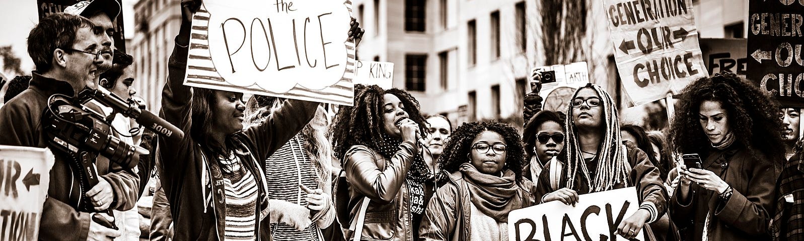 Mostly black women at a Black Lives Matter protest, with one holding a sign that says “Demilitarize the Police.”