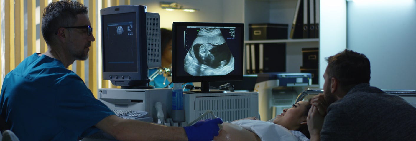 Medium close-up of a young couple watching ultrasound image of future child during ultrasound scan