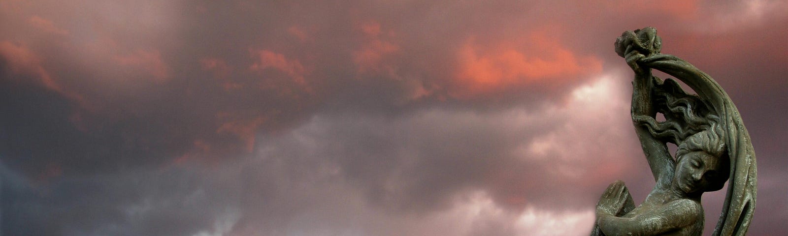 Color photo of a female statue that appears to be cowering before a stormy sky.