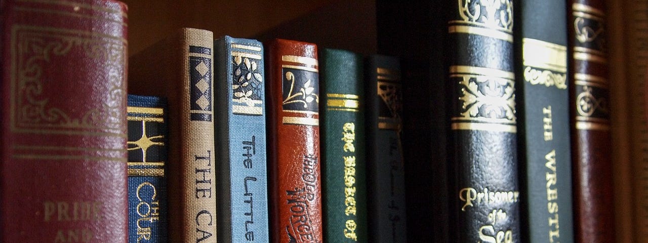 A close up of well kept older hardback books on a bookshelf.