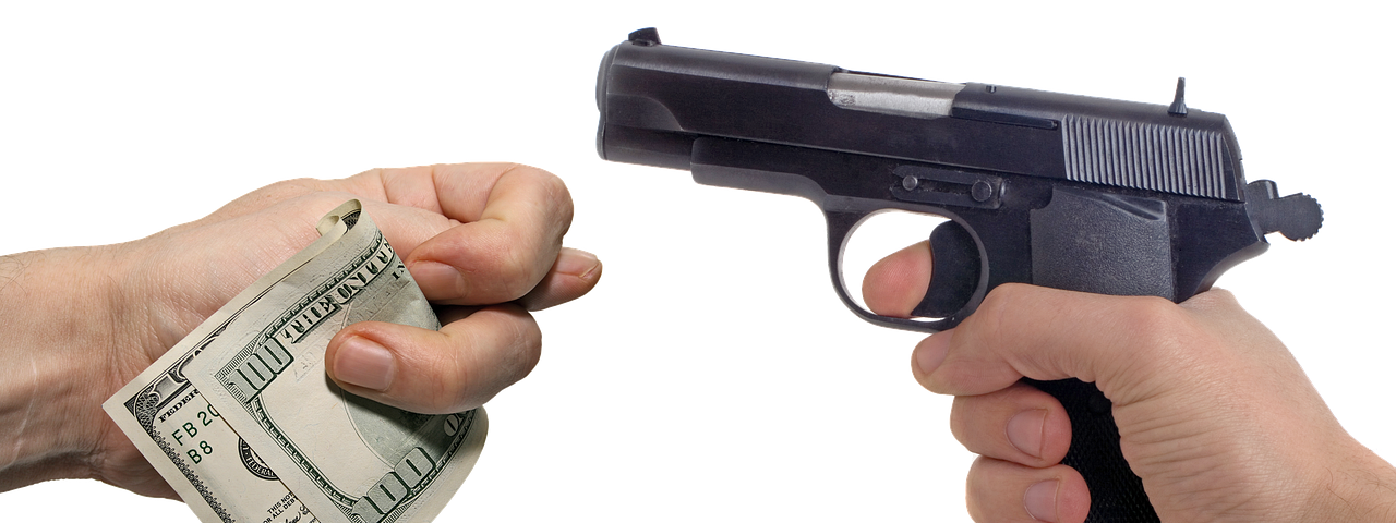IMAGE: A hand with a gun and another hand with some dollar bills