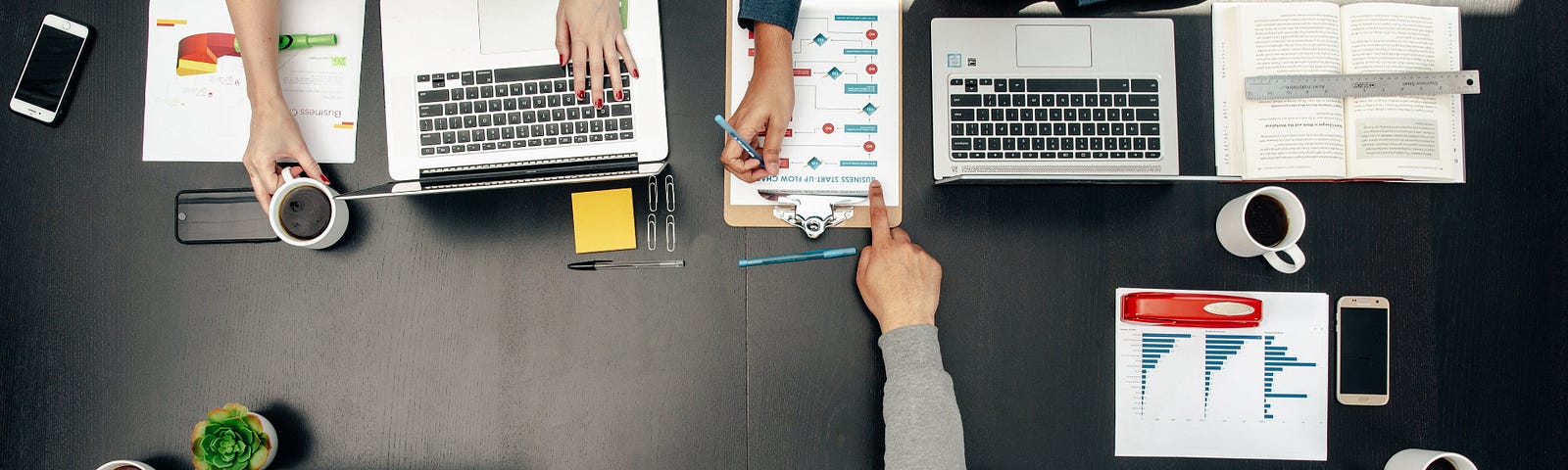 A picture showing office professionals around a desk, at work.