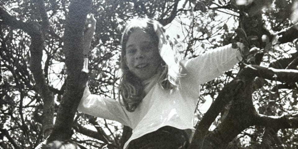 Black and white photo of Tara Brown as a young child climbing a tree.