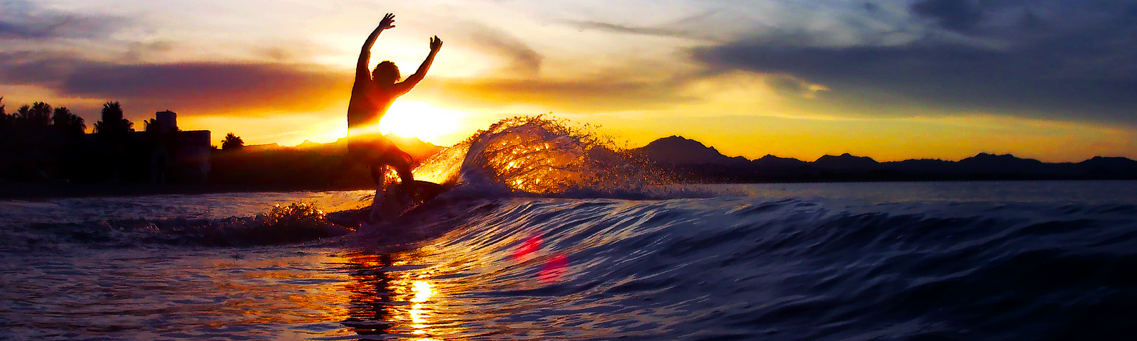 A man skimboarding in the surf at sunset (Photo Credit: Angelica Olson (me))