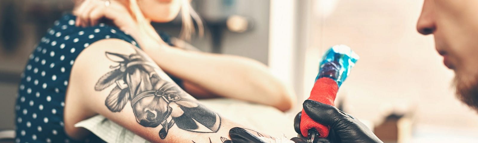 A woman getting a tattoo. A new study suggests getting a tattoo can boost your risk of getting one type of cancer.