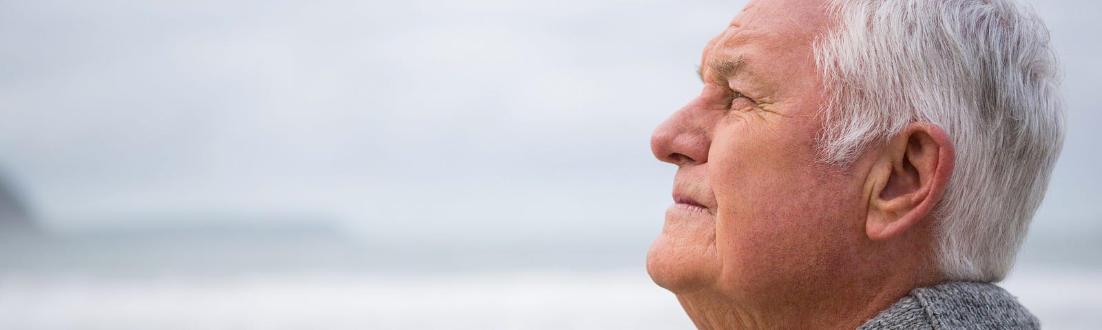 Older man staring out into unfocused and reflecting on thoughts
