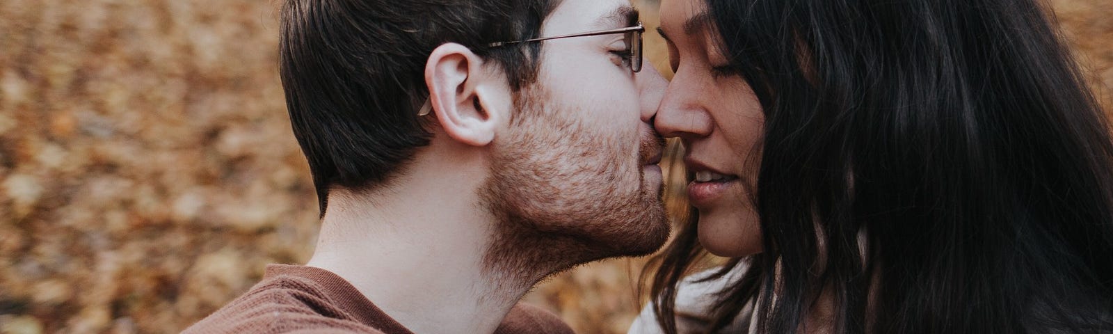 A couple embraces in a leafy park.