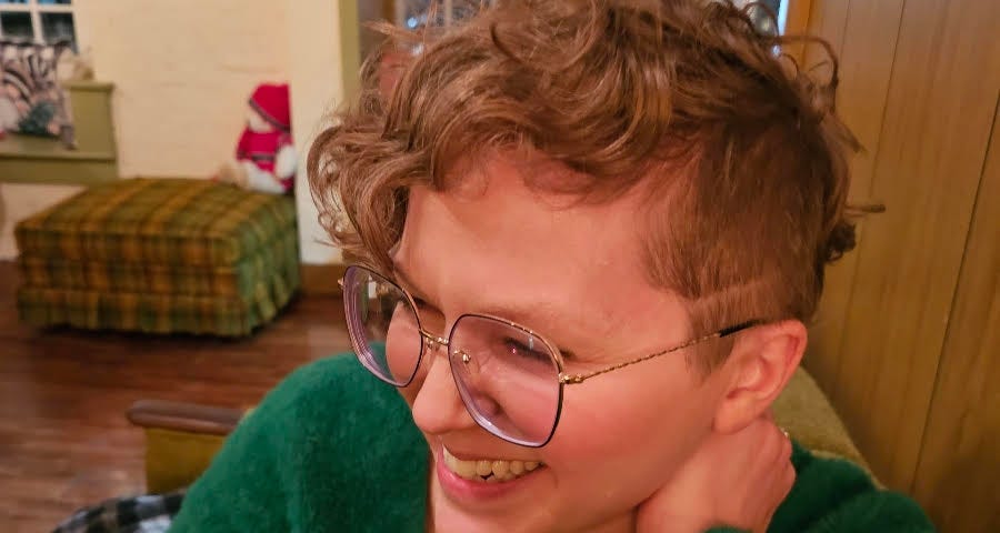 Candid photo of me smiling at my favorite bar, sporting my new asymmetrical curly bob.