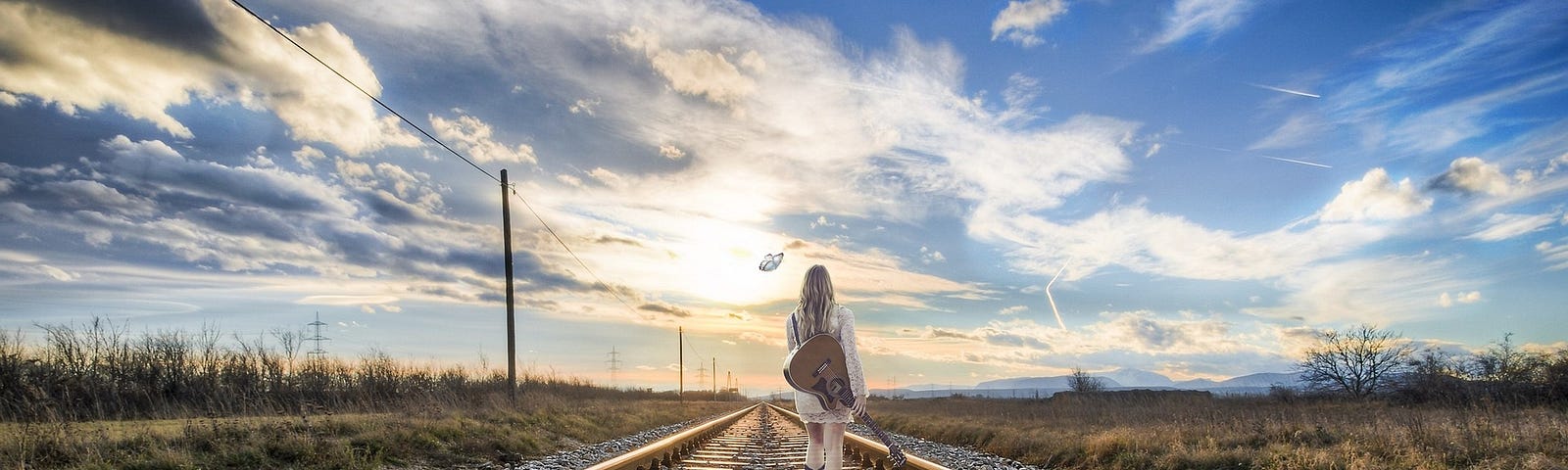 girl with guitar on train tracks