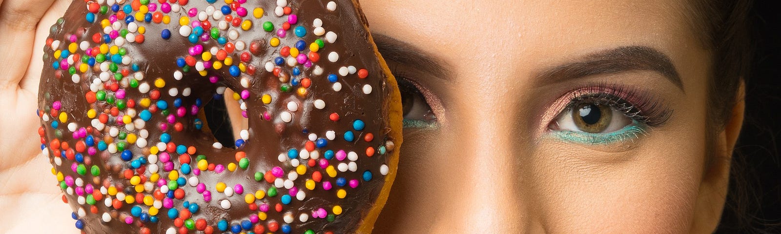 A young woman holds up a chocolate-covered doughnut