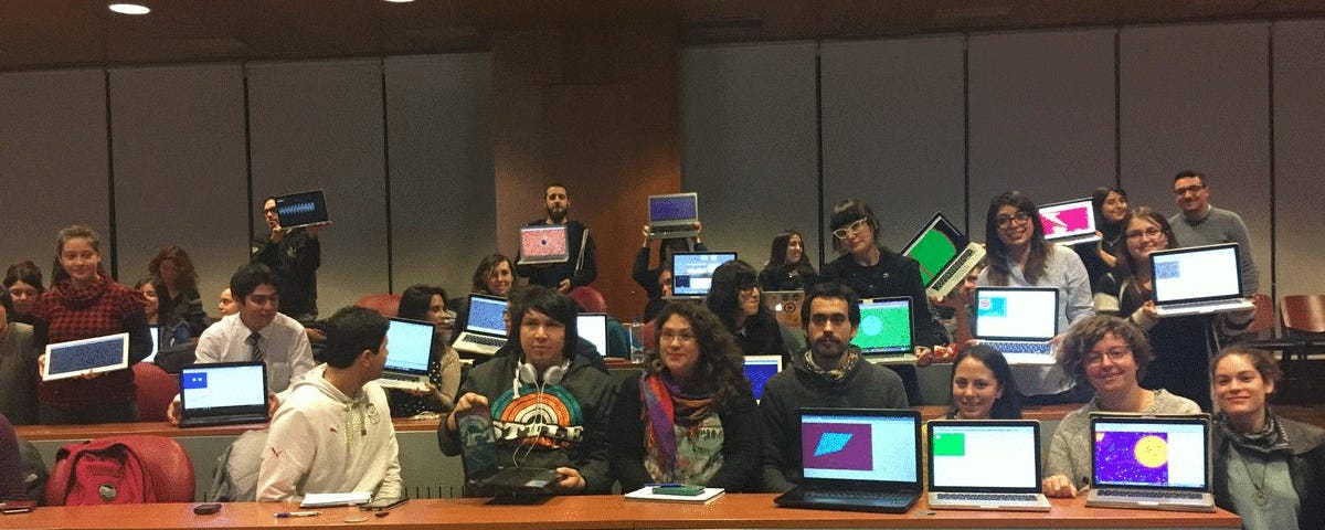 Large group of smiling artists display their laptops with first colorful sketches made with p5.js