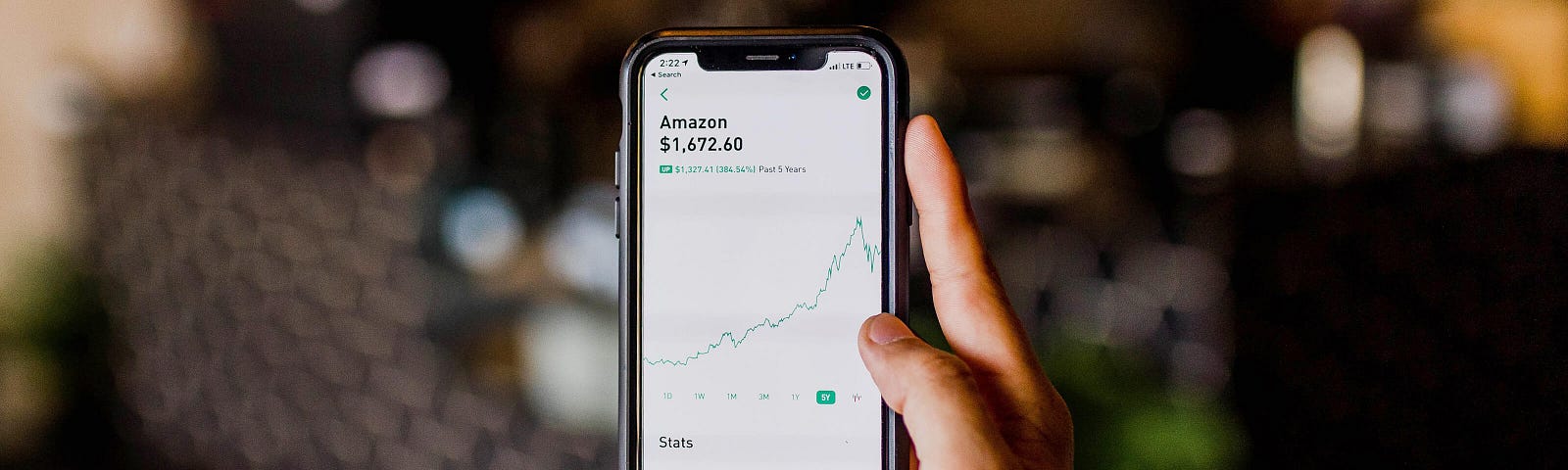 person holding smartphone with Amazon stock graph
