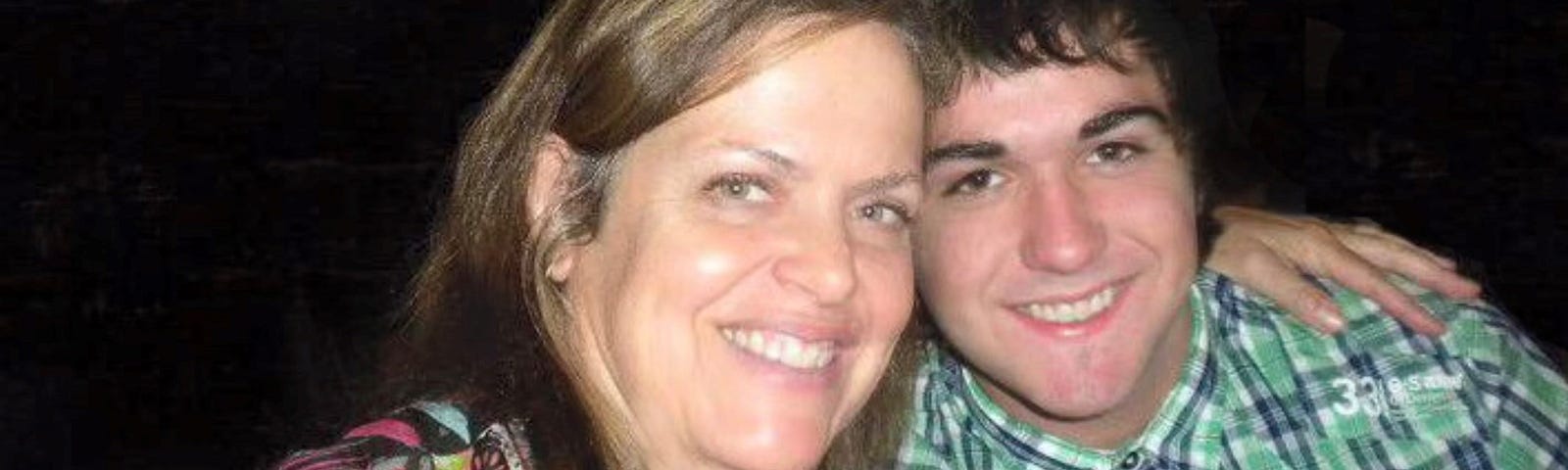 Photo of an attractive woman mid 30s to 40 with her 18-year-old son, who has dark hair and dark eyes.