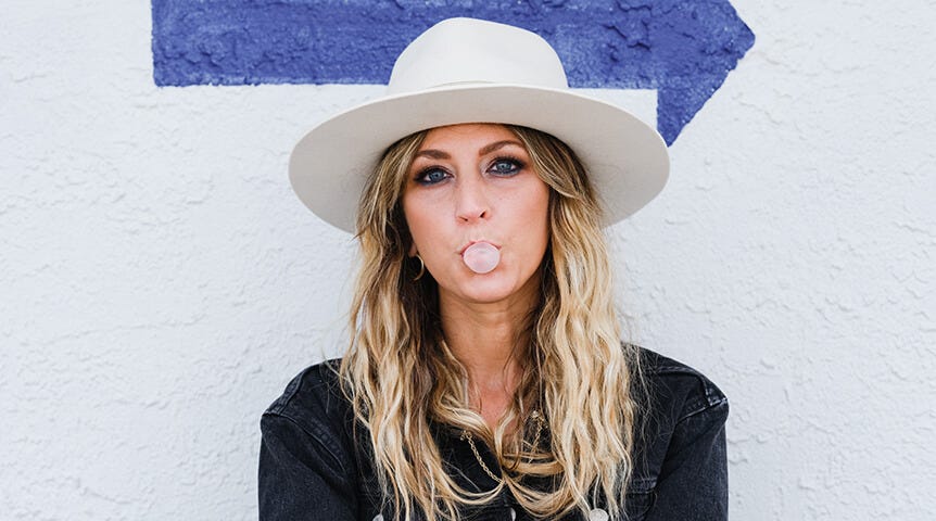 Blonde woman in white hat blowing bubble with gum