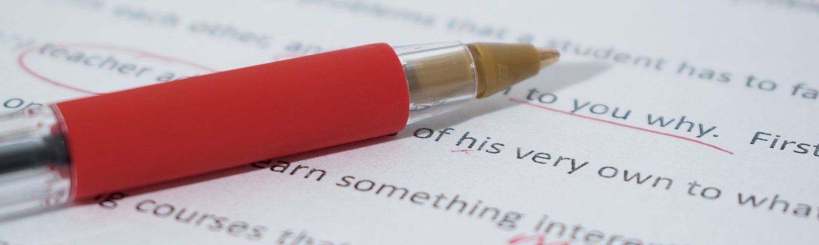 Red pen on top of a typed white paper with correction marks.